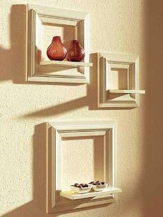 three framed pictures hang on the wall next to each other, one with two vases