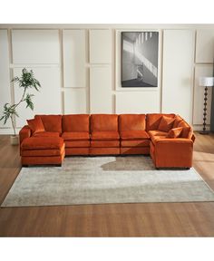 an orange sectional sofa in a living room with white walls and wood floors, along with a rug