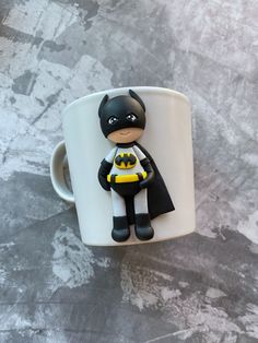 a batman figurine sitting on top of a white coffee cup in the shape of a mug