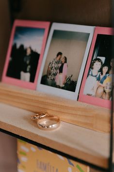 three polaroid photos on a wooden shelf with two wedding rings and one engagement ring