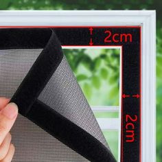 a hand holding a piece of black mesh over a white frame with the measurements for it