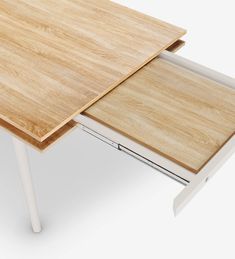 a wooden table with white legs and a laptop on it's side, in front of a white background