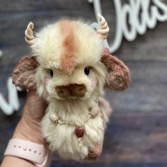 a small stuffed animal with horns on its head is held by a woman's hand