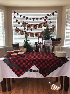 a red and black buffalo plaid table cloth on a dining room table with plates, cups, cake and decorations