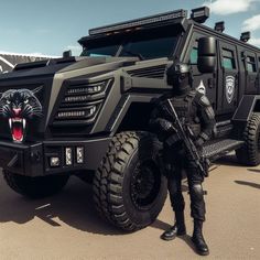 a man standing in front of a black armored vehicle with a tiger on the side