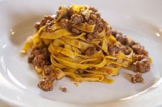 a white plate topped with pasta covered in sauce and ground meat on top of it