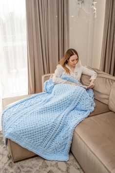 a woman sitting on a couch under a blue blanket