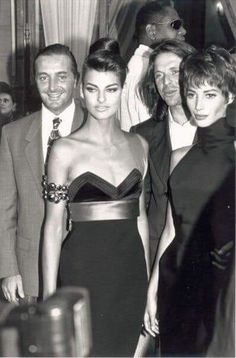 black and white photograph of three people standing next to each other in front of a crowd