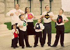 a group of people standing next to each other in front of a building with superman capes on