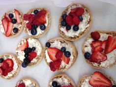 small pastries with strawberries and blueberries on them are arranged in a circle