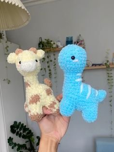 a person holding two small stuffed animals in their hands, one is blue and the other is brown