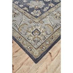 a blue and beige rug with an ornate design on the bottom, in front of a wooden floor