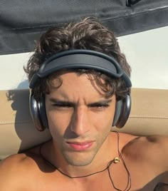 a shirtless man wearing headphones on top of a boat