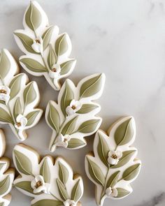 cookies decorated with green leaves and white flowers on a marble counter top text overlay reads, how to decorate sugar cookies