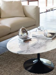 a white marble coffee table sitting on top of a carpeted floor next to a couch