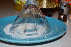 a blue plate topped with sugar and an upside down glass cone on top of it