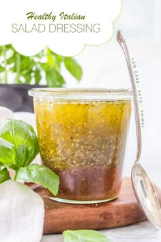 a jar filled with salad dressing sitting on top of a cutting board next to a spoon