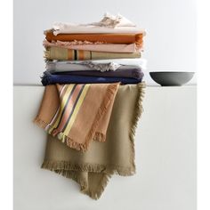 a stack of folded towels sitting on top of a white shelf next to a bowl