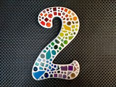 the number two is made up of multicolored circles and dots on a black background