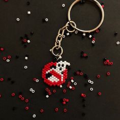 a keychain made out of legos and beads on a black surface with red, white, and black letters