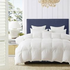 a white bed sitting next to a blue headboard and window with shutters on both sides