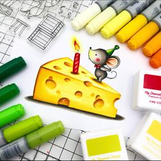 some crayons and markers are next to a piece of cheese with a candle on it