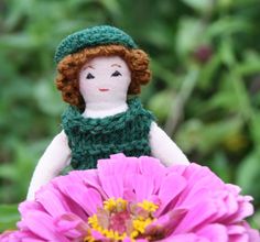 a doll sitting on top of a pink flower