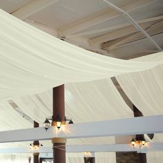 the ceiling is covered with white drapes and lights