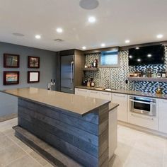 a large kitchen with an island in the middle and pictures on the wall behind it