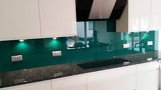 a kitchen with white cabinets and green glass counter tops on the backsplashes