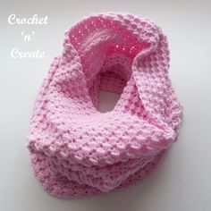 a pink crocheted scarf on a white surface