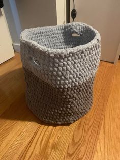 a gray basket sitting on top of a wooden floor