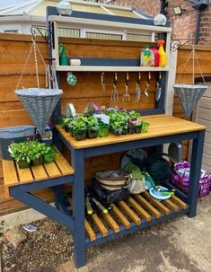 an outdoor garden with potted plants and gardening tools on the shelf next to it