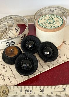 three spools of thread sitting on top of a measuring tape next to some scissors