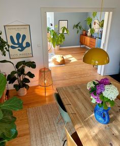 a dining room table with flowers in a blue vase on it and an open door leading to the living room