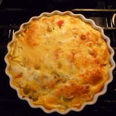 a casserole sitting on top of a stove next to a red pepper pot