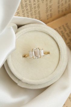 an engagement ring with three baguettes in it on top of a white cloth