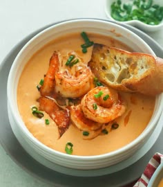 a bowl of soup with shrimp and bread