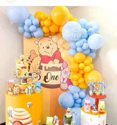 a winnie the pooh themed birthday party with balloons and desserts, including cake