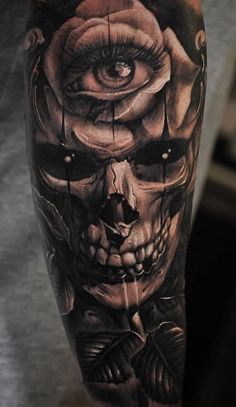 a man's arm with an evil skull and rose tattoo on the left forearm