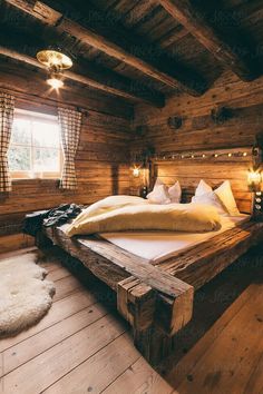 a large bed sitting inside of a wooden room next to a window with lights on it