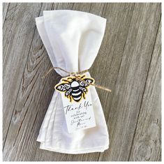 a white napkin with a yellow and black bee on it is tied to a wooden table