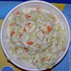 a bowl filled with coleslaw and carrots on top of a blue table