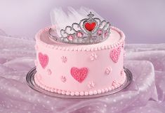 a pink cake decorated with hearts and a tiara