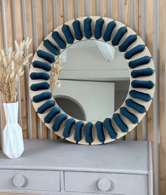 a mirror sitting on top of a dresser next to a vase