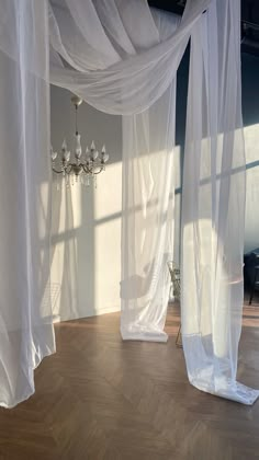 an empty room with white curtains and chandelier