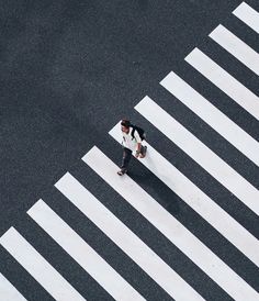 a man walking across a cross walk in the middle of an empty street with a backpack on his back