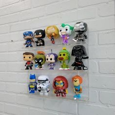 a bunch of pop - up action figures hanging on a white brick wall in a room