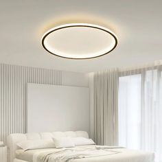 a white bed sitting under a round light in a bedroom