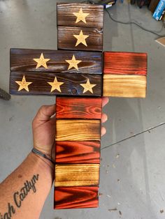 a person holding three wooden crosses with gold stars on them and one red, white, and blue flag painted on it